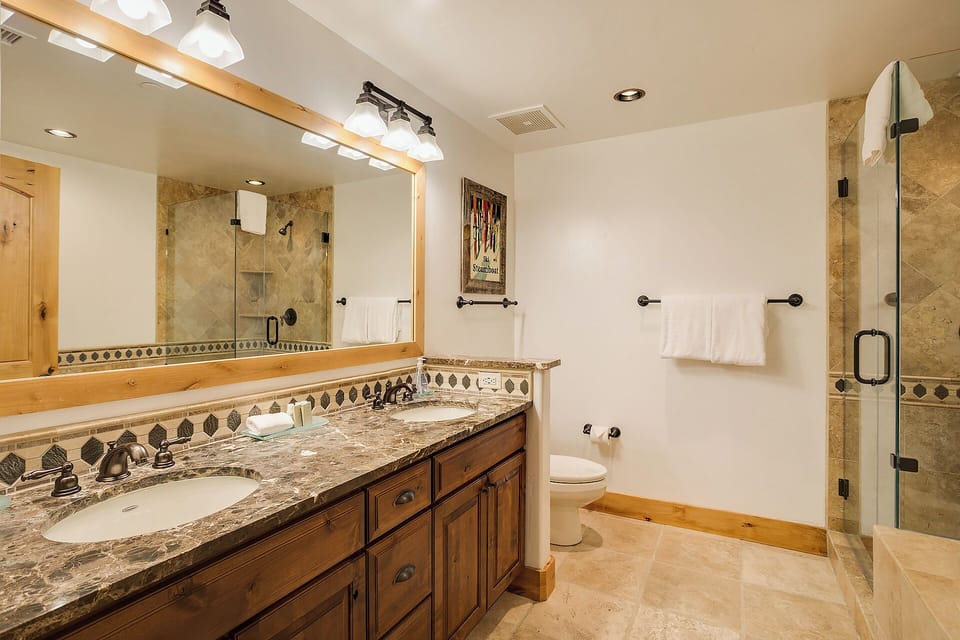 Unwind in your spacious bathroom with warm wood cabinetry, granite countertops, and a walk-in shower—perfect for refreshing after a day exploring the mountains.