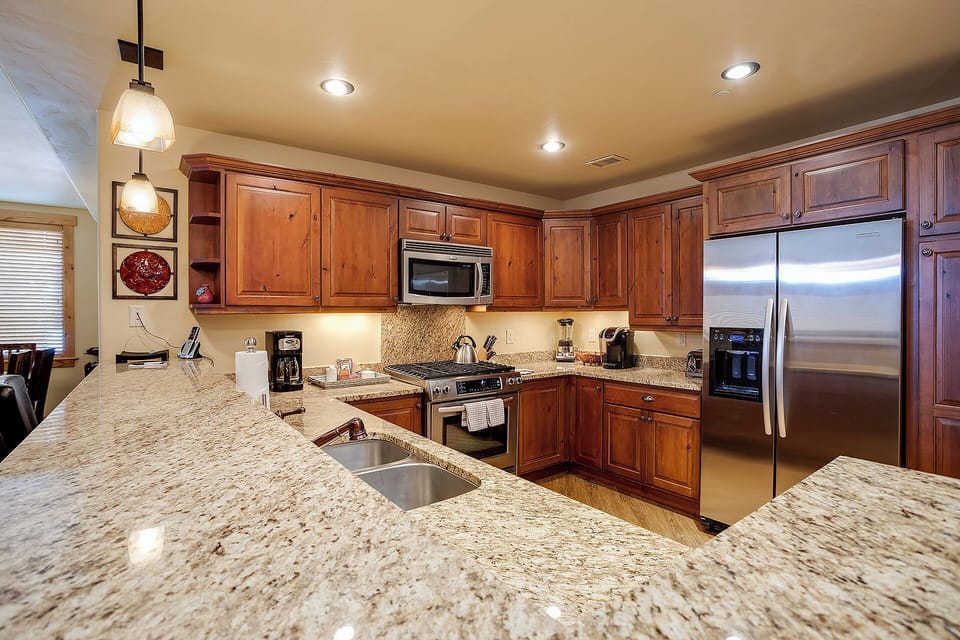 Your gourmet kitchen features warm cherry cabinetry, gleaming granite countertops, and modern stainless appliances—ready for memorable meals and morning coffee rituals during your stay.