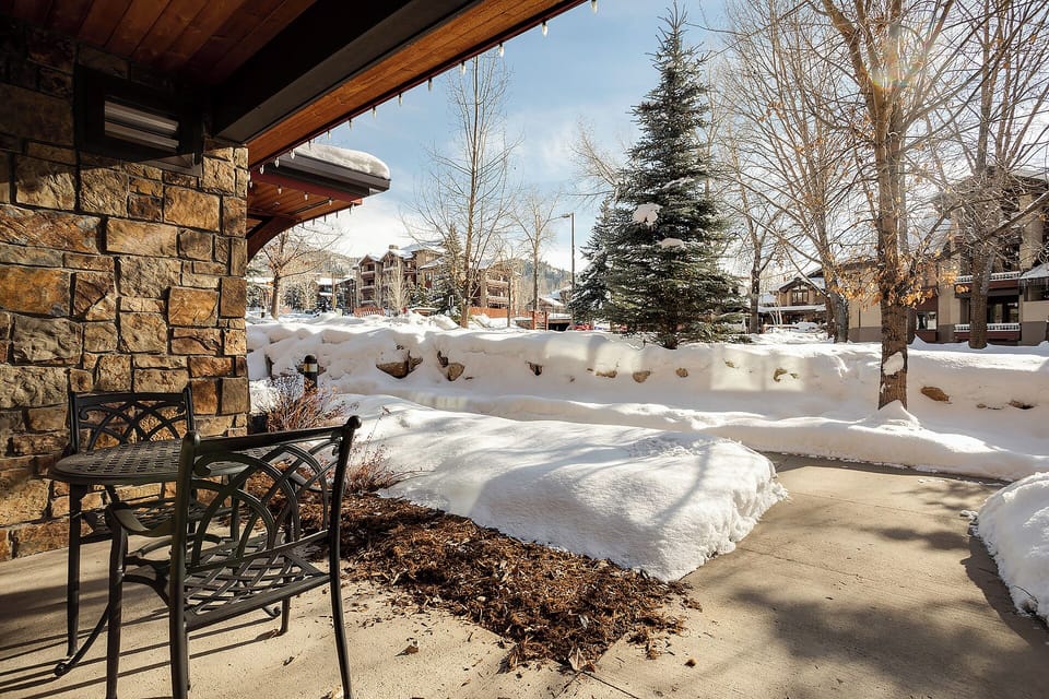A sun-drenched winter morning greets visitors arriving at this mountain property, where snow-covered evergreens and bare aspens frame a charming residential neighborhood nestled against scenic peaks.