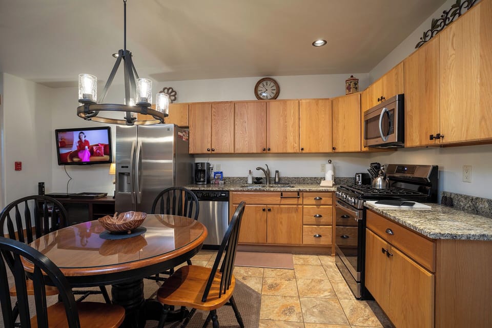 Your fully equipped kitchen and dining area invite you to prepare favorite meals while gathering with loved ones around the inviting table beneath warm lighting.