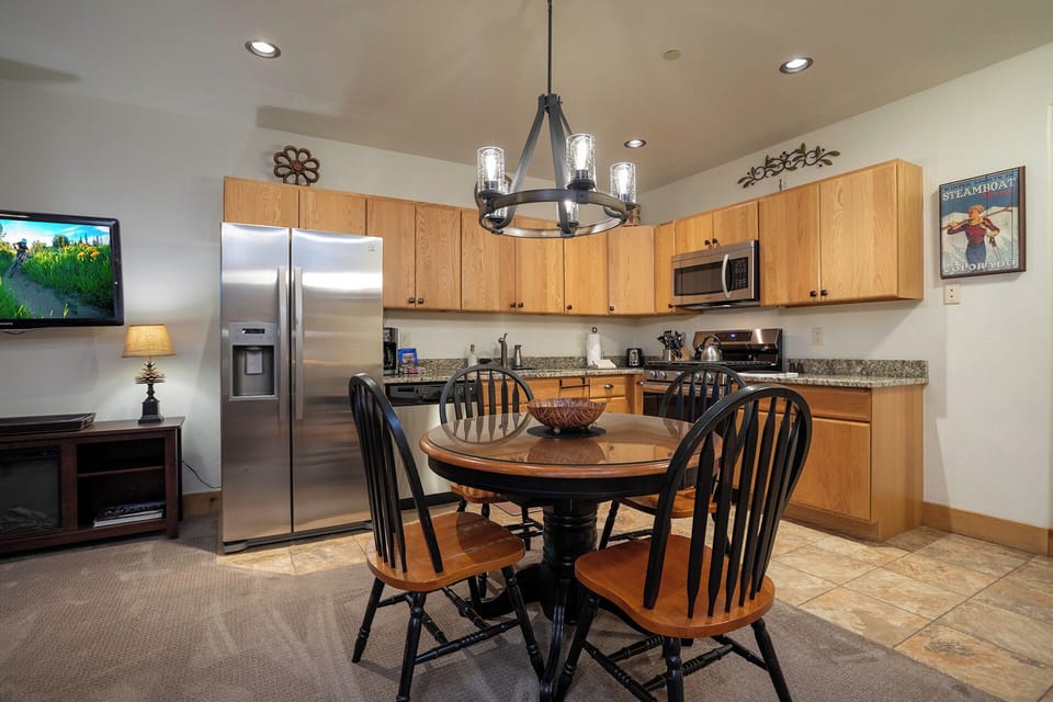 Gather around the inviting dining table in your fully equipped kitchen, where warm wood tones and modern appliances make cooking and sharing meals a joy.