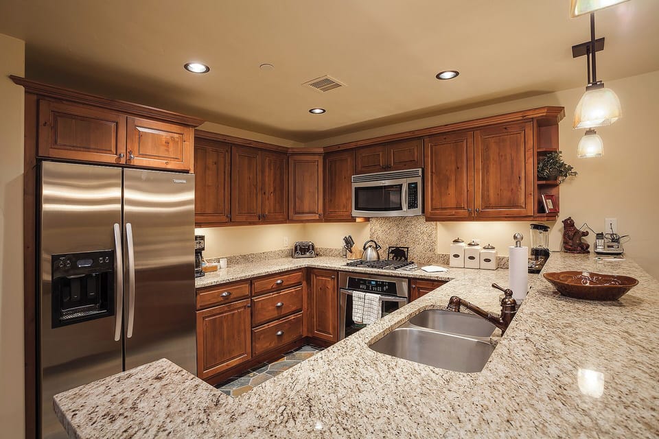 Your fully equipped kitchen features granite counters, stainless appliances, and rich wood cabinetry—perfect for preparing meals or enjoying morning coffee in comfort.