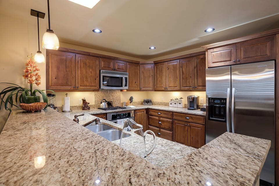 This fully equipped gourmet kitchen invites you to prepare delicious meals on gleaming granite countertops, surrounded by warm wood cabinetry and stainless steel appliances—perfect for your culinary adventures.