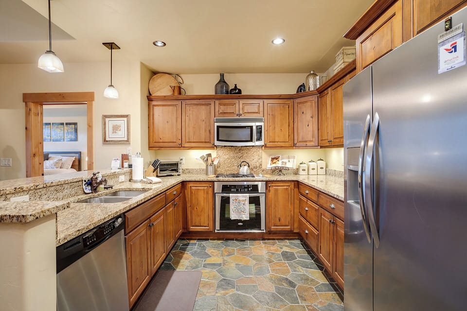 This fully-equipped kitchen features warm wood cabinetry, granite countertops, and stainless steel appliances—everything you need to whip up delicious meals during your mountain getaway.