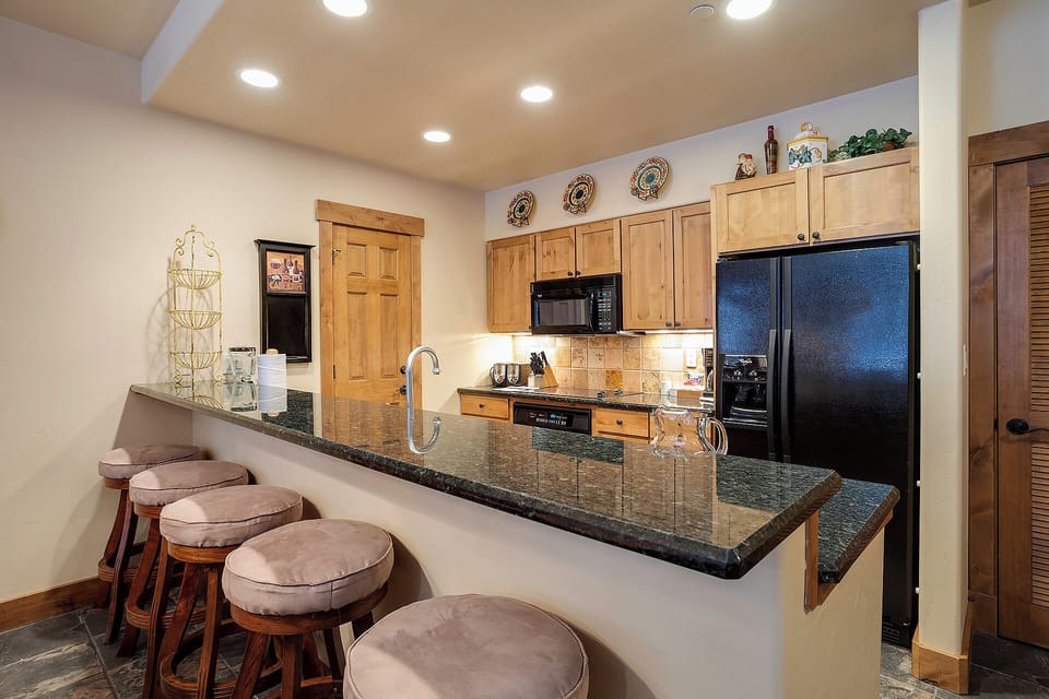 Your fully-equipped kitchen awaits, complete with granite counters, stainless appliances, and a breakfast bar where you can sip your morning coffee and plan your day's adventures.