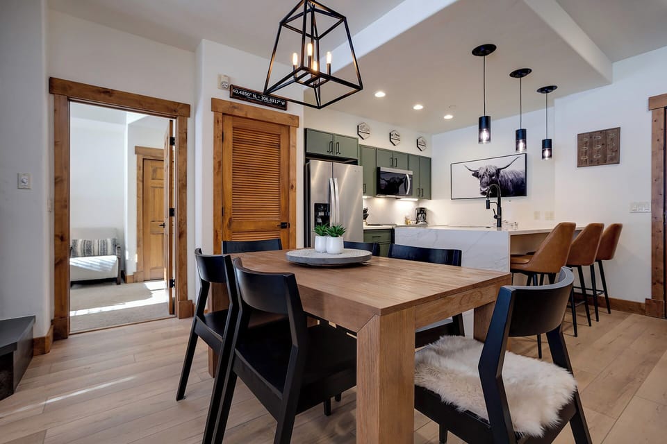 Gather around the large wooden dining table, where modern mountain design meets thoughtful comfort. Your fully-equipped kitchen invites meal prep, while elegant pendant lighting sets the mood for memorable evenings together.
