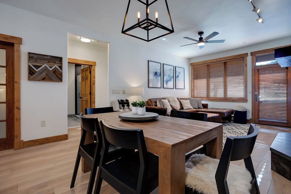 Gather around the solid wood dining table where warm modern fixtures and natural light create your perfect space for shared meals and memorable conversations.