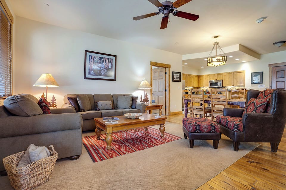 Sink into plush sofas and unwind in your spacious open-concept living area, where rustic mountain charm meets modern comfort with warm wood tones, cozy lighting, and plenty of room to gather.