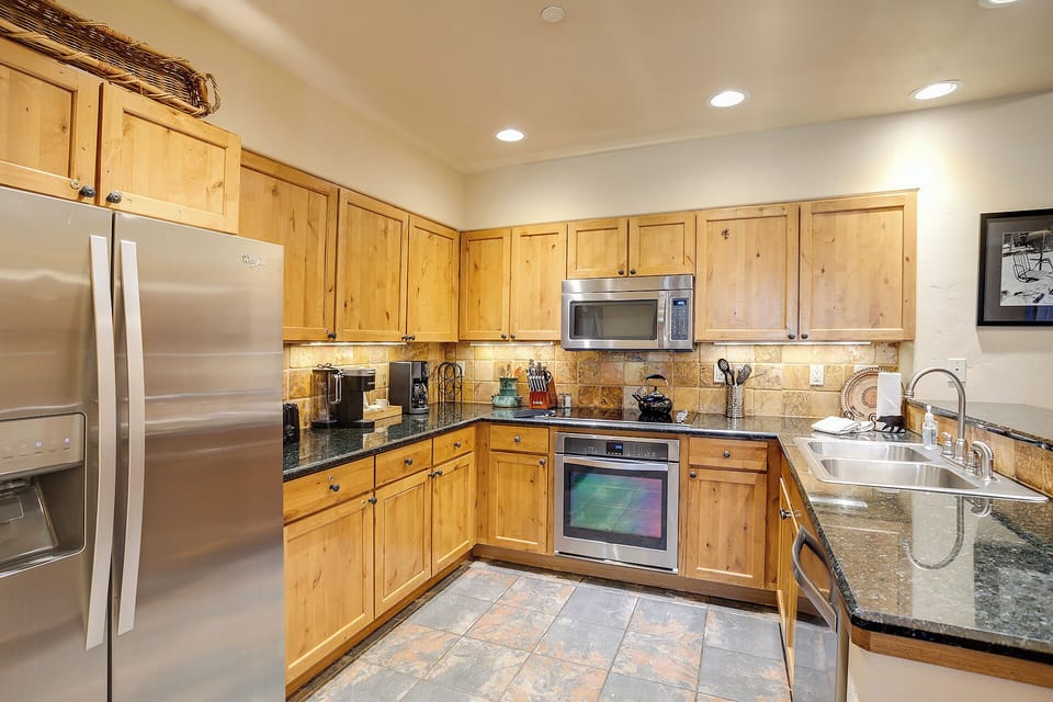 Your fully equipped kitchen awaits with stainless steel appliances, granite countertops, and warm knotty pine cabinetry—perfect for preparing home-cooked meals during your mountain getaway.