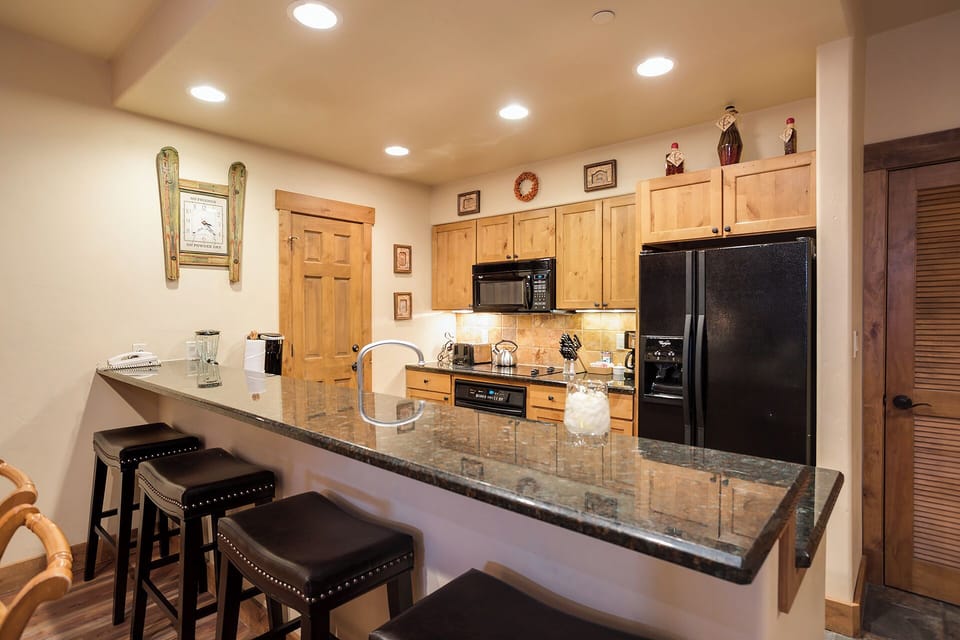 Gather at your granite breakfast bar and discover a fully-equipped kitchen ready for cooking together, complete with modern appliances and warm wood cabinetry.