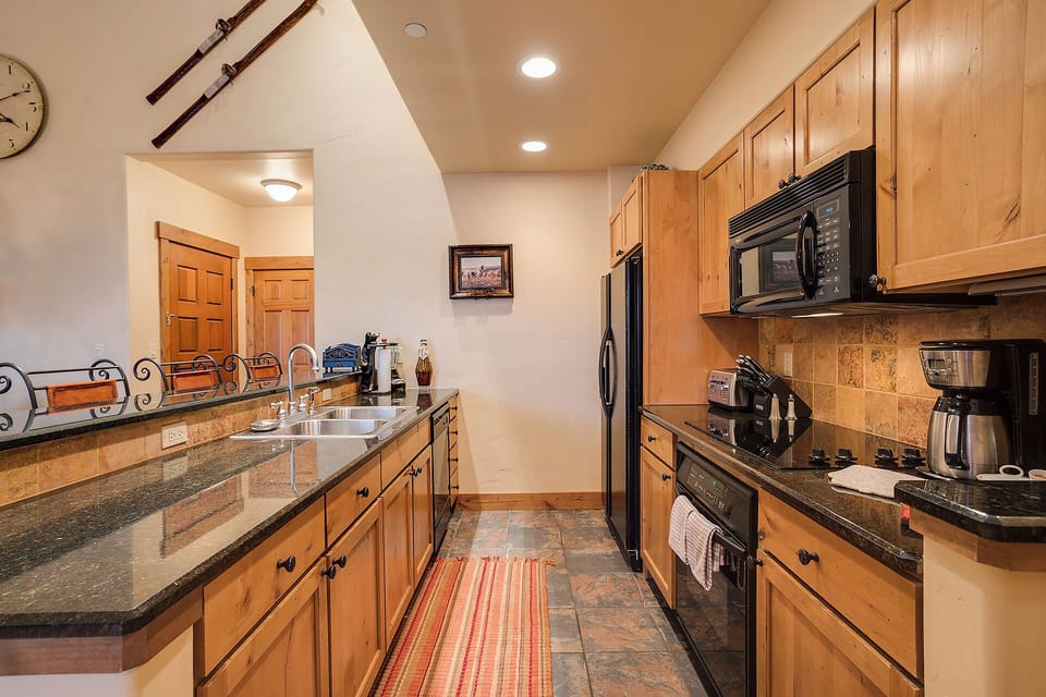 Step into your fully equipped kitchen with granite counters, modern appliances, and warm wood cabinetry—perfect for whipping up meals or morning coffee during your mountain getaway.