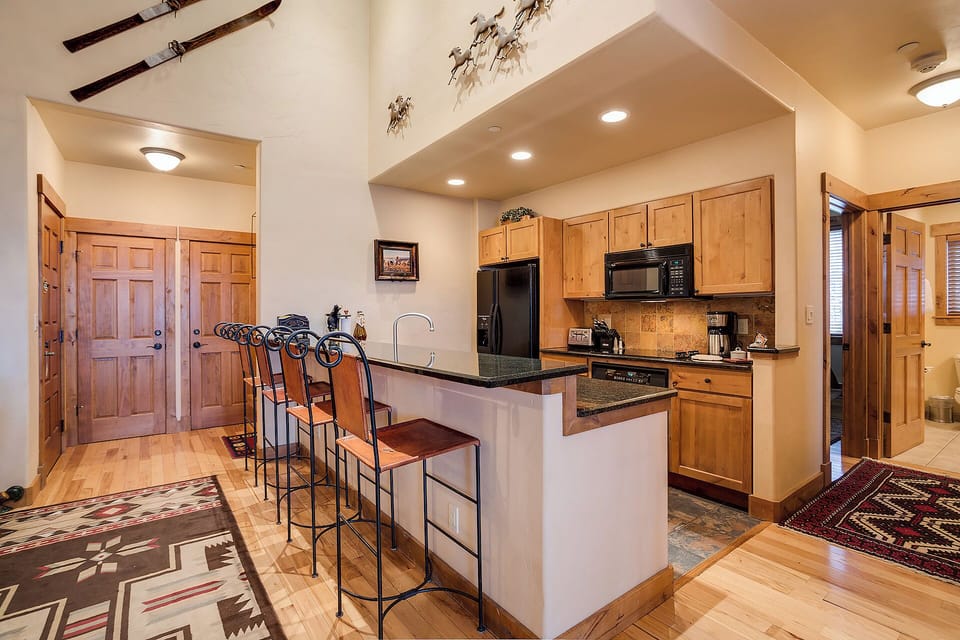 Step into your mountain retreat featuring a fully equipped kitchen with granite counters, modern appliances, and a breakfast bar perfect for morning coffee or casual dining together.