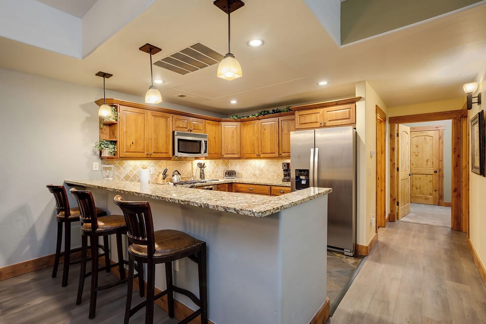 Your fully-equipped kitchen welcomes you with warm wood cabinetry, granite counters, and stainless appliances—perfect for preparing meals or gathering around the breakfast bar with loved ones.