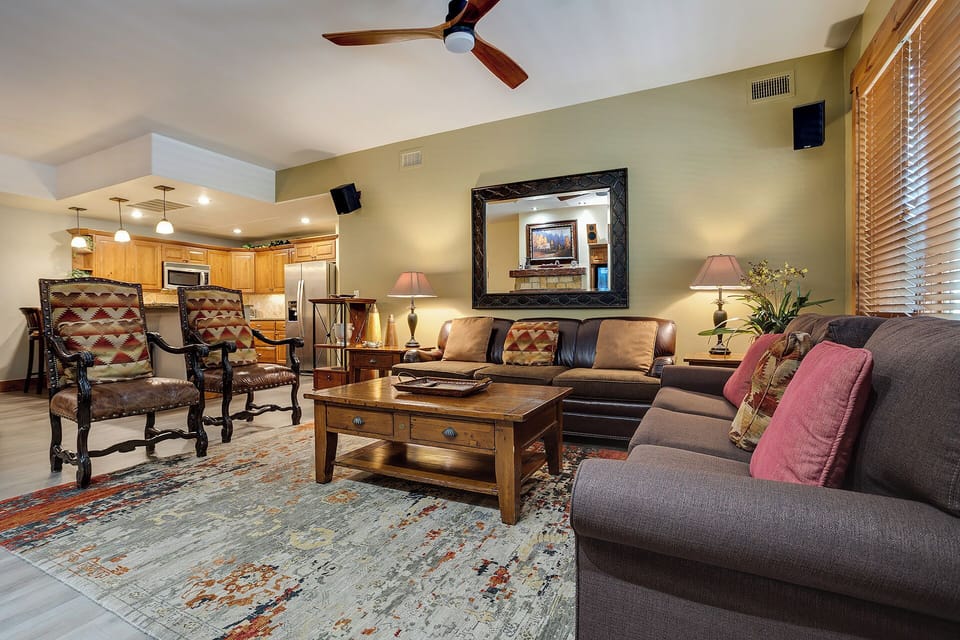 Step into your spacious living room where rich leather and plush seating await beneath vaulted ceilings. Unwind on the comfortable sofas, enjoy the open flow to the kitchen, and feel instantly at home.