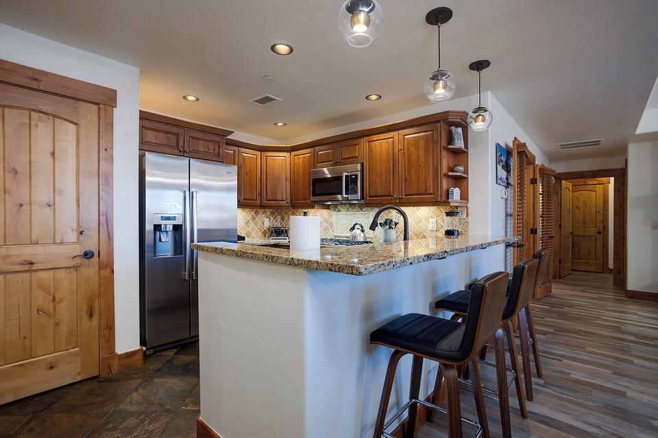Gather around the spacious island in your fully equipped kitchen, where warm wood cabinetry, granite countertops, and modern appliances set the stage for memorable meals together.