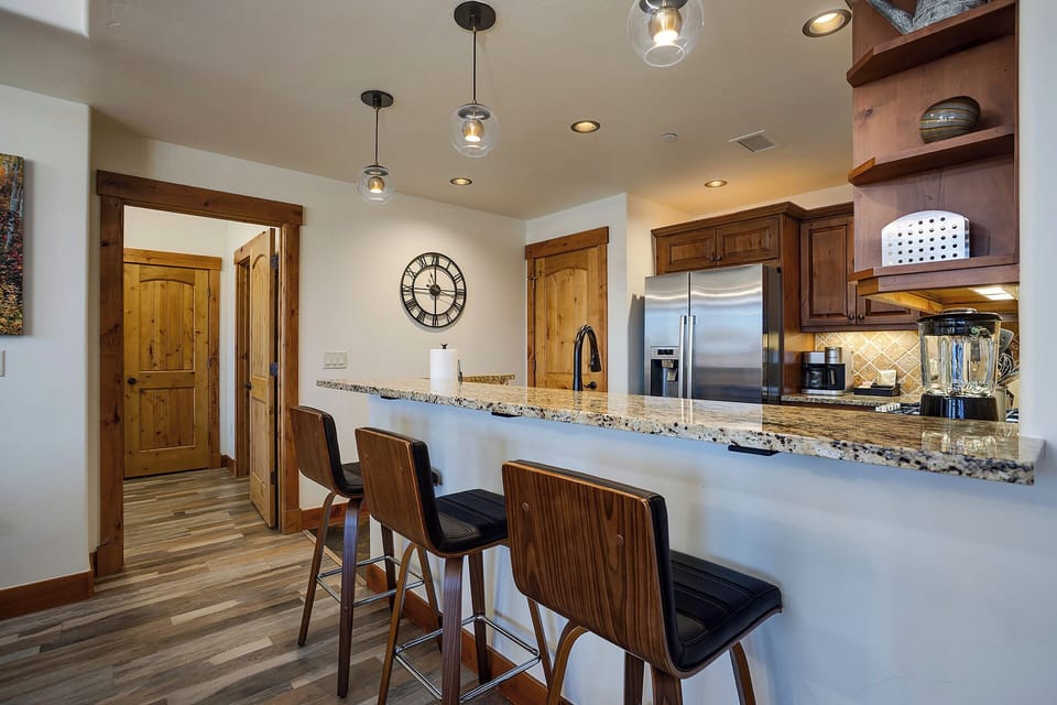 Gather around the sleek breakfast bar with cozy seating, perfect for morning coffee or casual meals. The granite countertops, modern lighting, and fully equipped kitchen make your stay feel effortlessly at home.