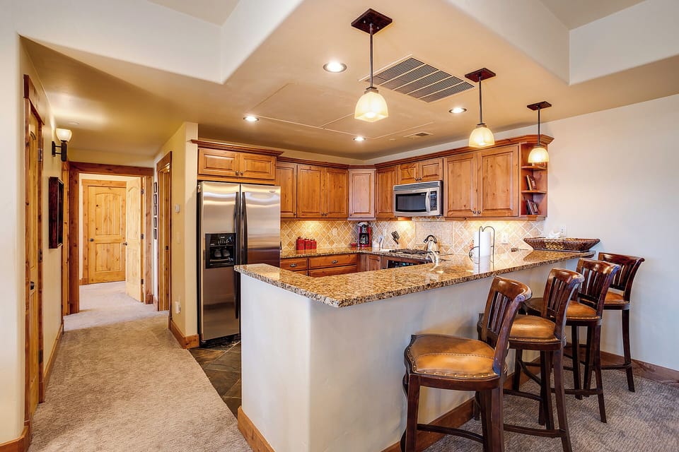 Gather around this inviting kitchen island with granite counters, rich wood cabinetry, and sleek stainless appliances—perfect for morning coffee or preparing meals together.