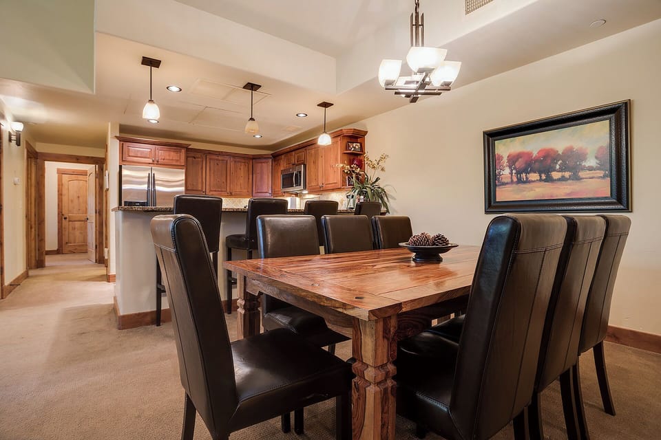 Gather around the handcrafted wood table in your open-concept dining and kitchen space, where rich leather chairs and warm wood tones create the perfect setting for memorable meals together.