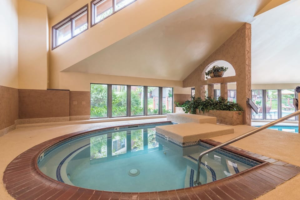 Step into your private oasis: a sunlit indoor pool with high ceilings, tropical accents, and garden views—perfect for refreshing dips any time of day.