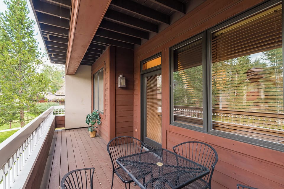 A covered balcony with a small dining table surrounded by trees offers your peaceful outdoor retreat, perfect for morning coffee or evening relaxation overlooking the natural surroundings.