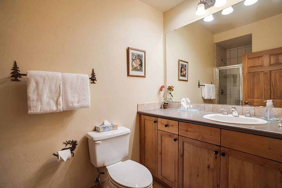 Your private bathroom features rustic wooden cabinetry, soft towels, and thoughtful touches like fresh flowers, creating a cozy and inviting retreat after a day of mountain adventures.