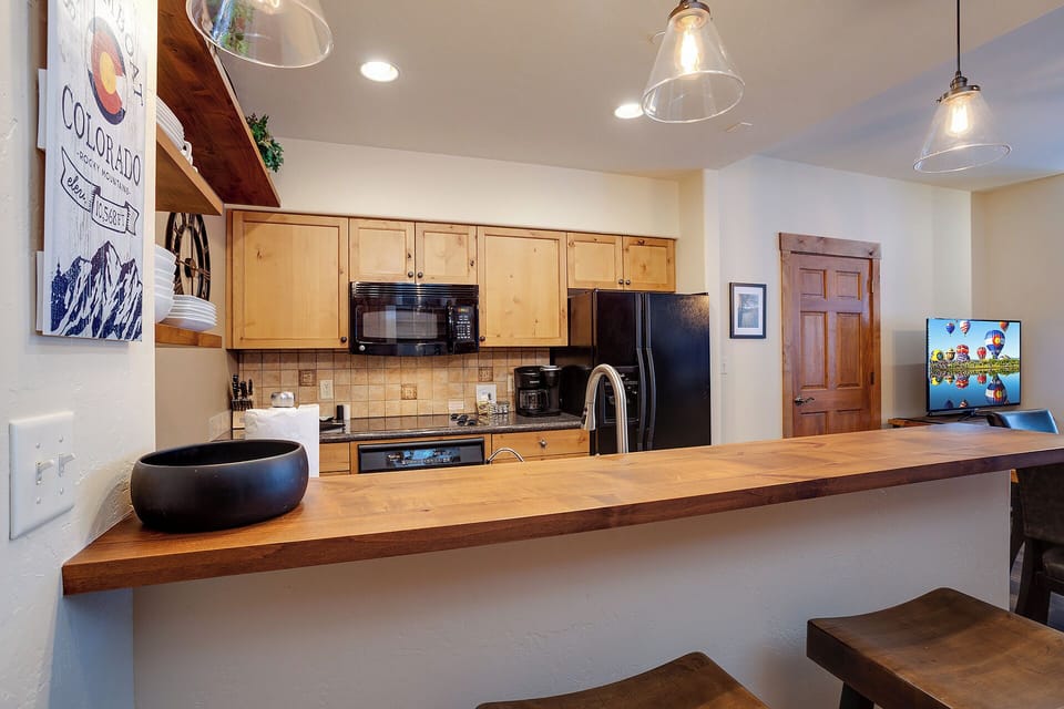 Your fully equipped kitchen invites you to craft memorable meals at the spacious wooden counter, where modern appliances and mountain-inspired charm blend effortlessly.