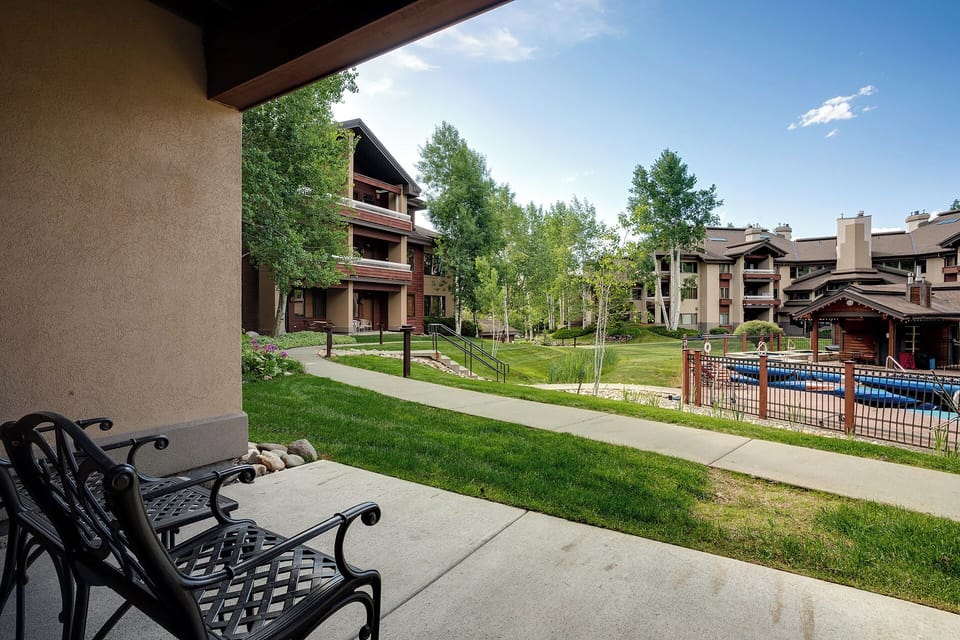 Your private patio overlooks landscaped grounds where towering aspens frame mountain views and a sparkling pool invites you to unwind after a day of adventure.