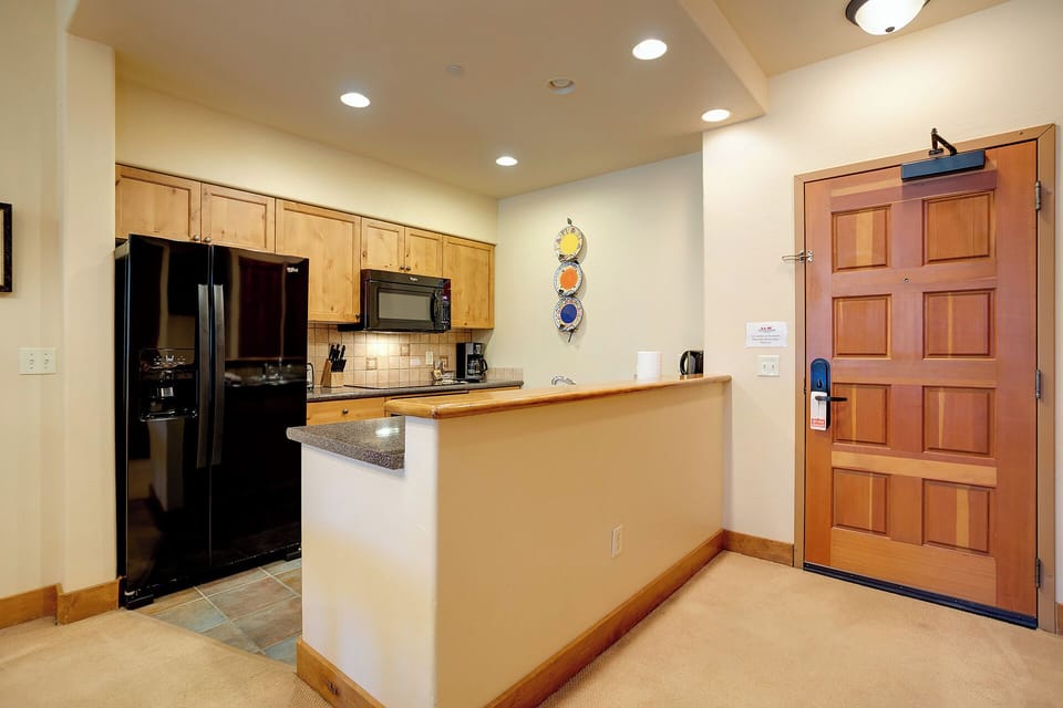 Step into your fully equipped kitchen, where warm wood cabinetry, modern appliances, and a breakfast bar invite you to prepare delicious meals and gather with loved ones during your mountain getaway.