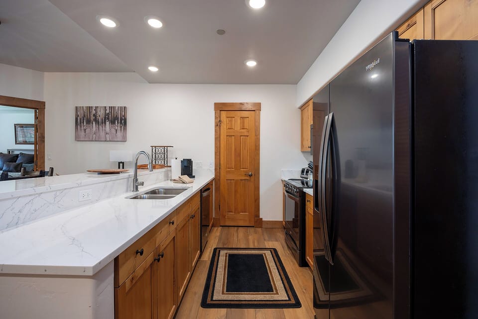 Your fully equipped kitchen features elegant marble countertops, modern stainless appliances, and warm wood cabinetry—perfect for preparing meals or morning coffee during your mountain getaway.