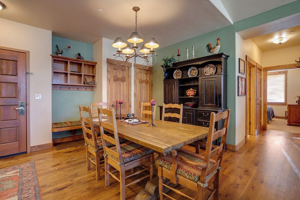 Gather around the rustic farmhouse table beneath warm pendant lighting, with charming country touches and custom cabinetry creating a welcoming space for meals and memories.