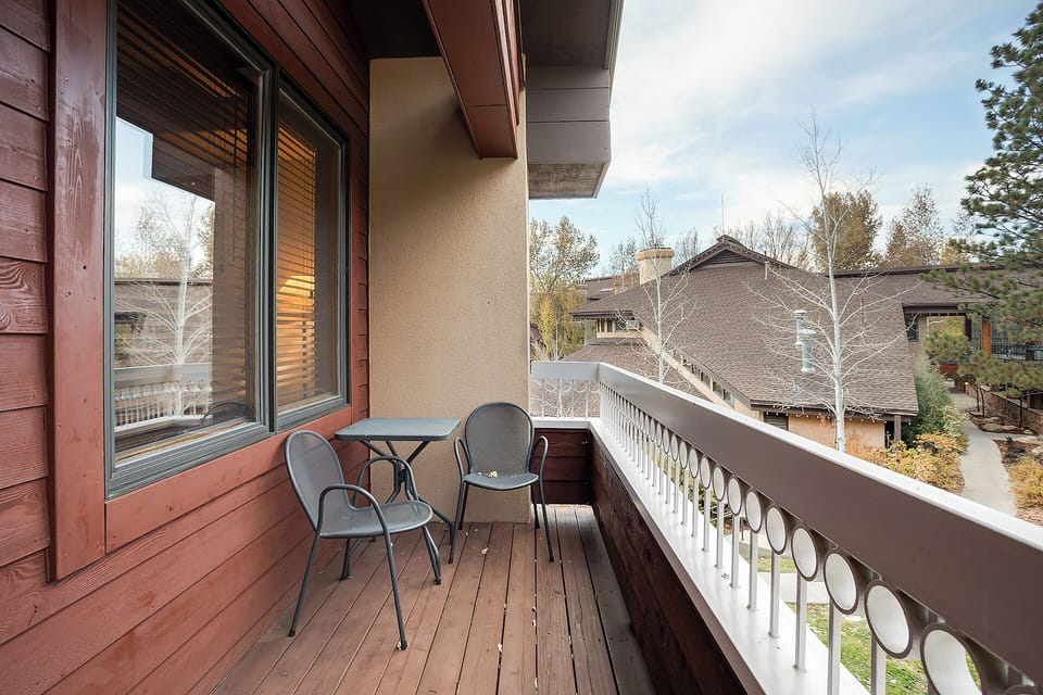Private balcony features seating area overlooking a quiet residential neighborhood surrounded by autumn foliage and mountain trees—perfect for morning coffee or evening relaxation in the fresh alpine air.