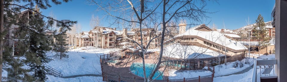Winter wonderland surrounds this property, featuring stunning snow-covered grounds, an inviting heated pool, and beautiful mountain architecture framing your alpine getaway.