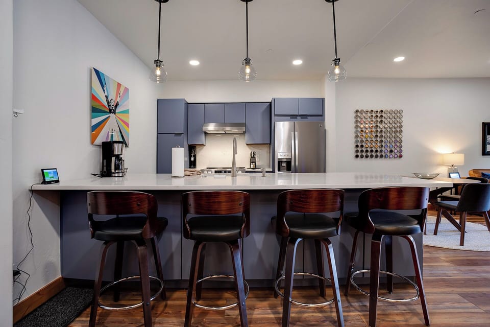 Gather around this sleek breakfast bar with modern pendant lighting, where mornings start with coffee and conversation in your fully-equipped kitchen space.