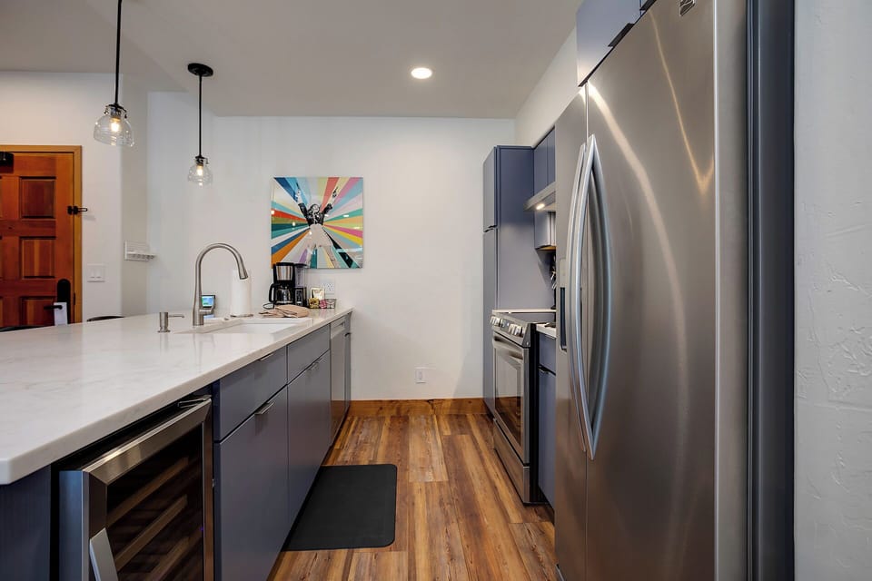 Modern kitchen featuring sleek stainless steel appliances, marble countertops, and custom cabinetry. You'll love preparing meals in this stylish, well-equipped space with coffee maker and premium finishes.