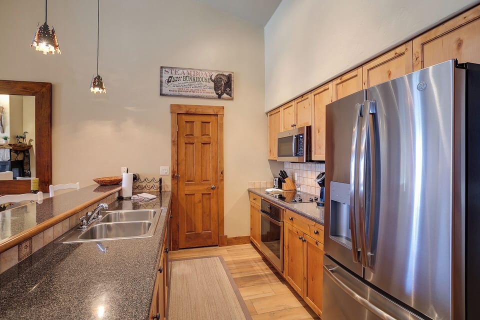 Your fully equipped galley kitchen features stainless steel appliances, granite countertops, and warm wood cabinetry—perfect for preparing meals together after a day exploring nearby trails.