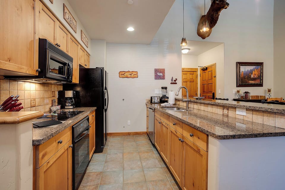 Your fully equipped mountain kitchen features granite counters, rich wood cabinetry, and modern appliances—perfect for preparing meals together after a day of adventure.