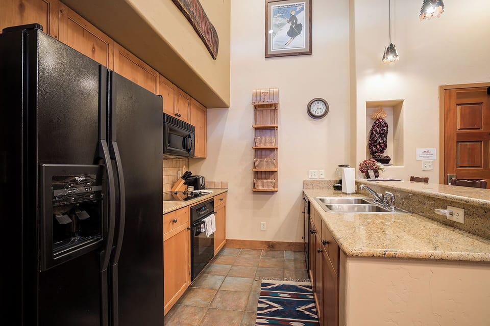 Your fully equipped kitchen features granite countertops, modern appliances, and warm wood cabinetry—everything you need to prepare meals comfortably during your mountain getaway.