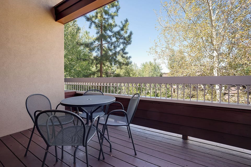A private balcony surrounded by towering pines and golden autumn trees offers a peaceful retreat. Enjoy your morning coffee at the intimate bistro table while soaking in the serene, tree-lined views.