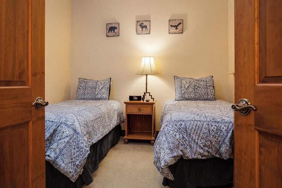 Twin beds dressed in rustic-inspired linens await you in this cozy, wildlife-themed bedroom. The warm glow of the bedside lamp and charming wall art create a welcoming mountain retreat.