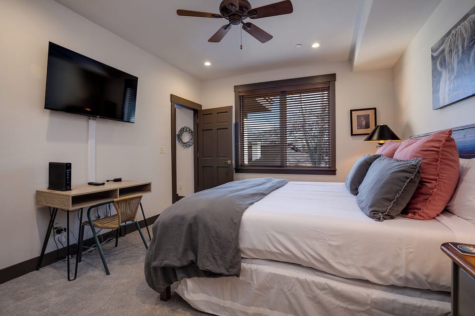 Unwind in your serene bedroom with a plush bed, calming decor, and a workspace—your peaceful retreat after a day exploring the area.