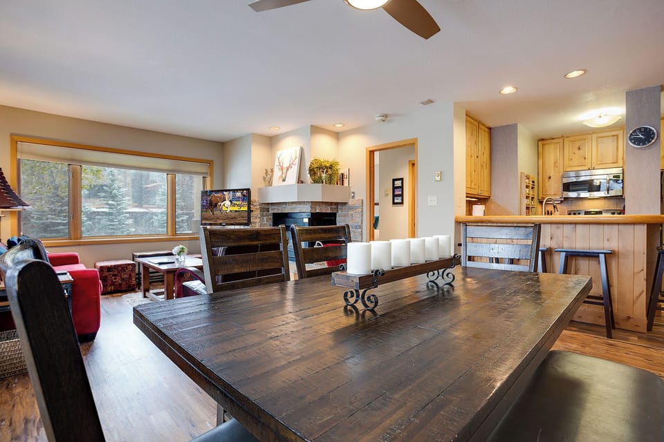 Gather around this handsome dining table and soak in mountain views through wide windows. Your open-plan retreat flows seamlessly into a cozy living room and well-appointed kitchen—perfect for après-ski evenings.