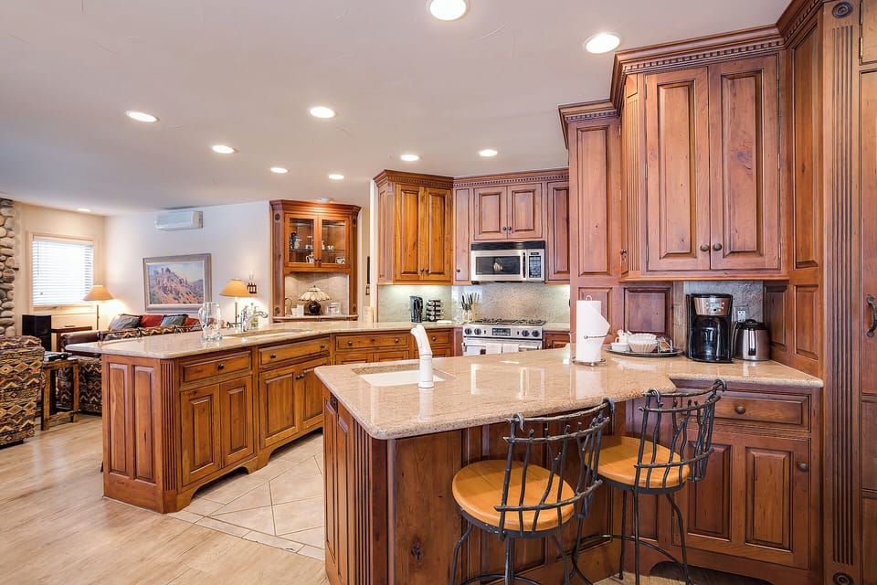 Your gourmet kitchen features rich wood cabinetry, granite counters, and a spacious island with seating—perfect for preparing meals or sipping morning coffee in style.