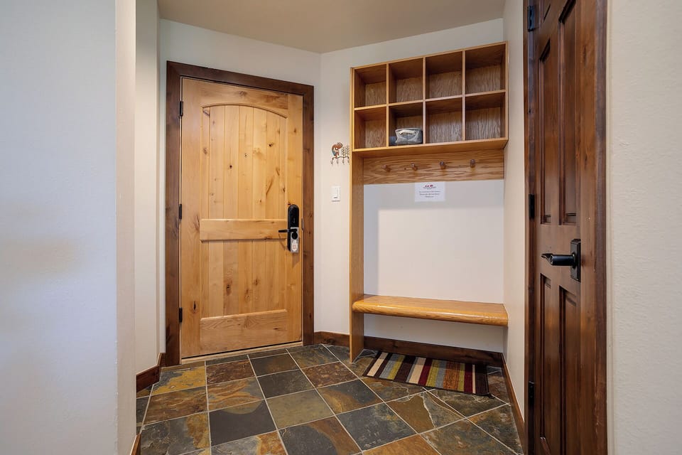Step into your mountain retreat through this welcoming entryway, where custom woodwork and slate tile flooring set a warm, rustic tone. Thoughtful storage keeps your gear organized for your next adventure.