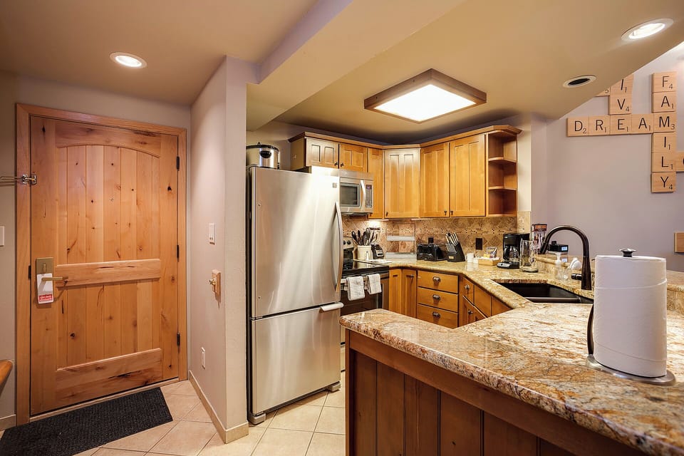Your fully equipped kitchen features granite counters, stainless appliances, and warm wood cabinetry—perfect for preparing meals during your mountain getaway.
