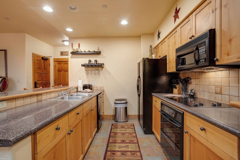 Your fully-equipped galley kitchen with modern appliances, ample counter space, and warm wood cabinetry makes meal prep effortless and enjoyable during your mountain getaway.