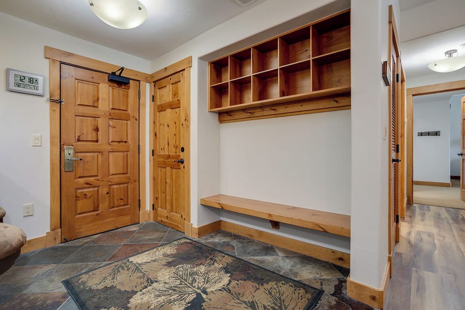 Organized entryway with custom wooden storage cubbies and bench keeps your gear tidy after mountain adventures. Durable slate-style flooring and rustic wood details add warmth and functionality to your arrival.