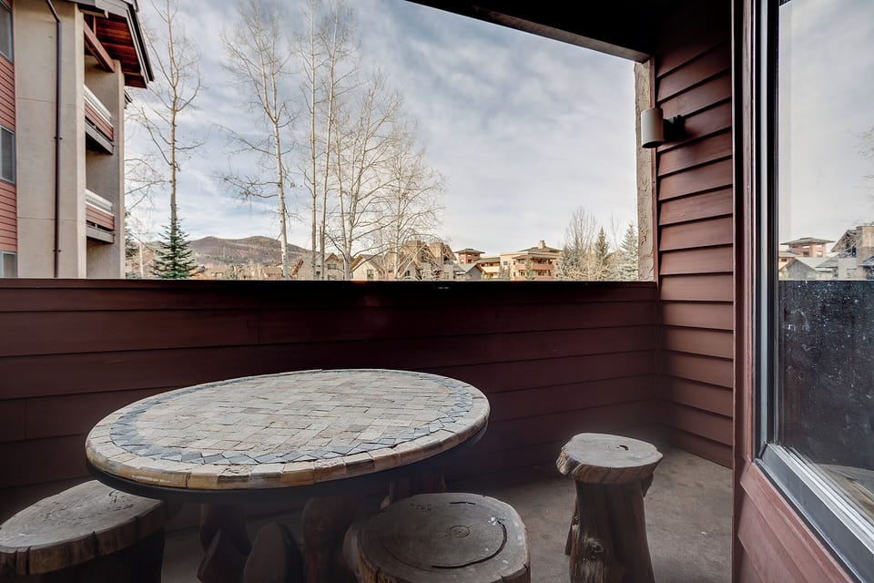 Private balcony with rustic stone table and mountain views—perfect for morning coffee or evening relaxation in the crisp mountain air.