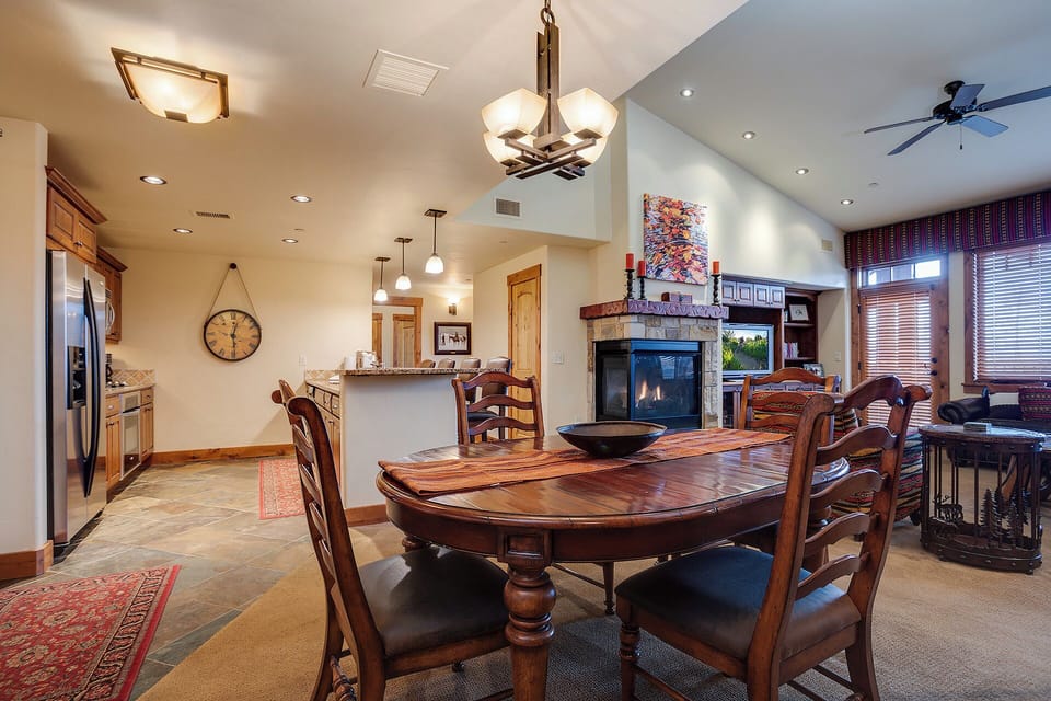 Gather with loved ones in this open-concept living space, where a handcrafted dining table, cozy fireplace, and fully equipped kitchen create the perfect setting for your mountain getaway.