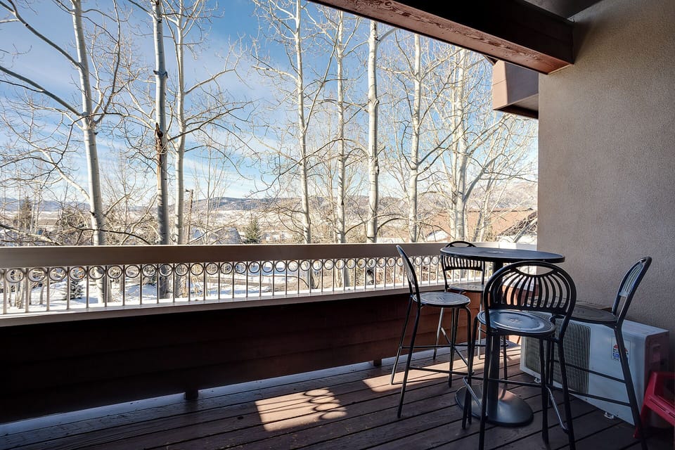 Private balcony overlooking snow-dusted aspens and mountain vistas, framed by sweeping blue skies and peaceful winter scenery beyond the property.