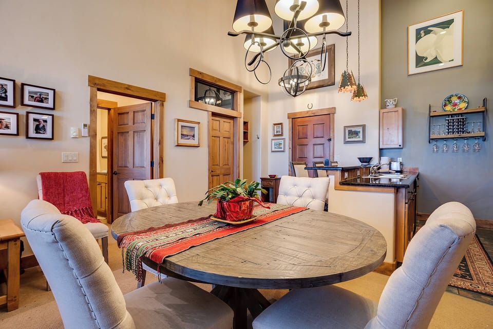 Step into your inviting dining space with vaulted ceilings and warm wood accents. Gather around the rustic round table for memorable meals, bathed in the glow of elegant chandeliers.